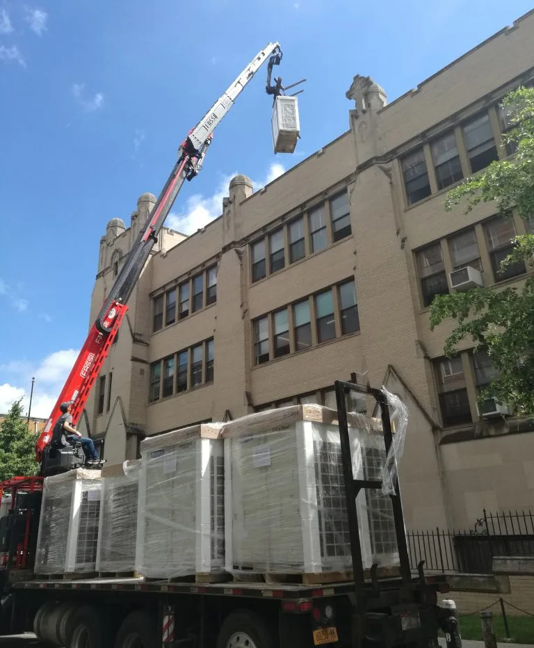 Crane lifting HVAC equipment onto a New York school rooftop — JJR Mechanical