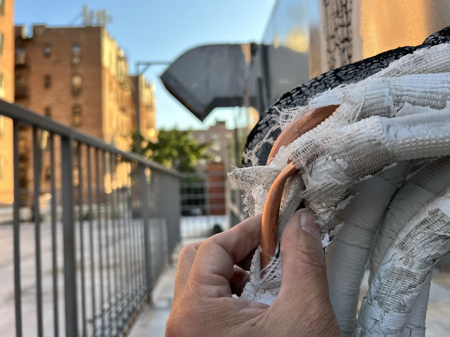 Deteriorated line-set insulation on a rooftop refrigerant run, inspected before repair
