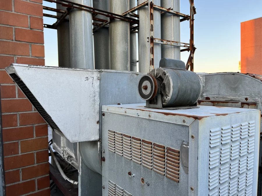 Belt-drive exhaust fan motor and pulley showing corrosion, inspected during rooftop ventilation service