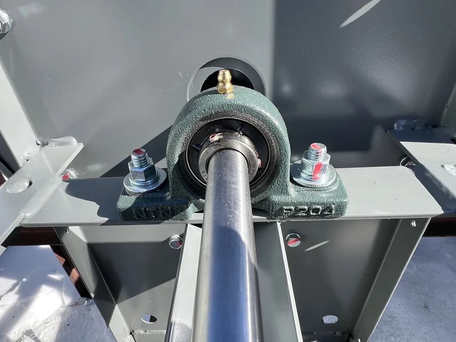 New pillow-block bearing and grease fitting on an exhaust fan shaft, bolts torque-marked after replacement